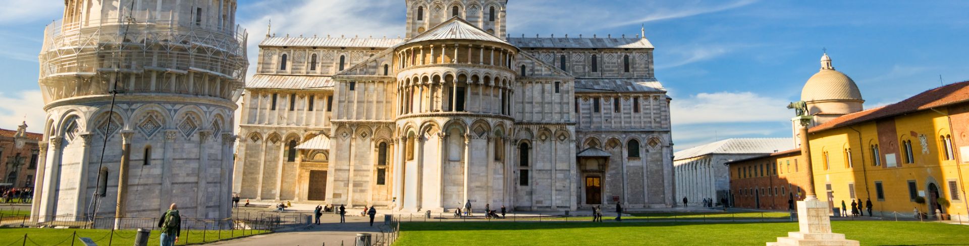 The view of a grey marble medieval cathedral next to the Leaning Tower of Pisa.