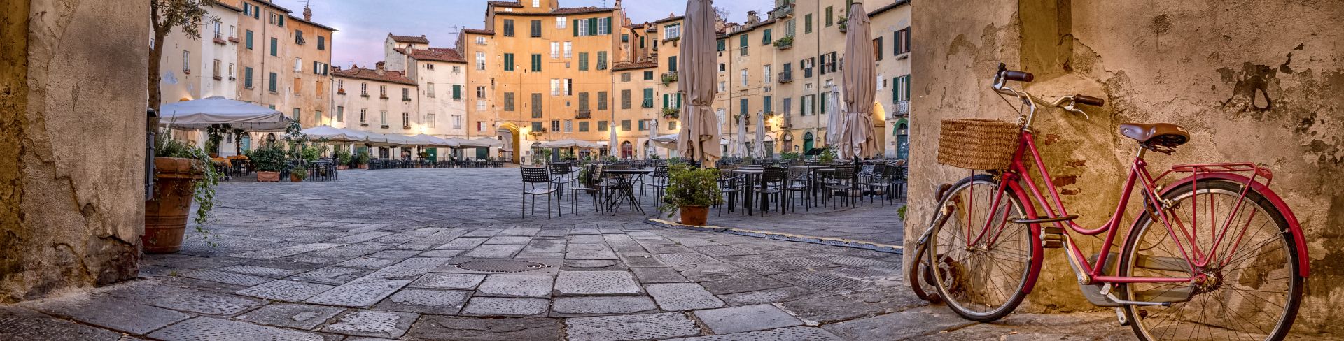 A bicycle leaning against a wall adjacent to a large square.
