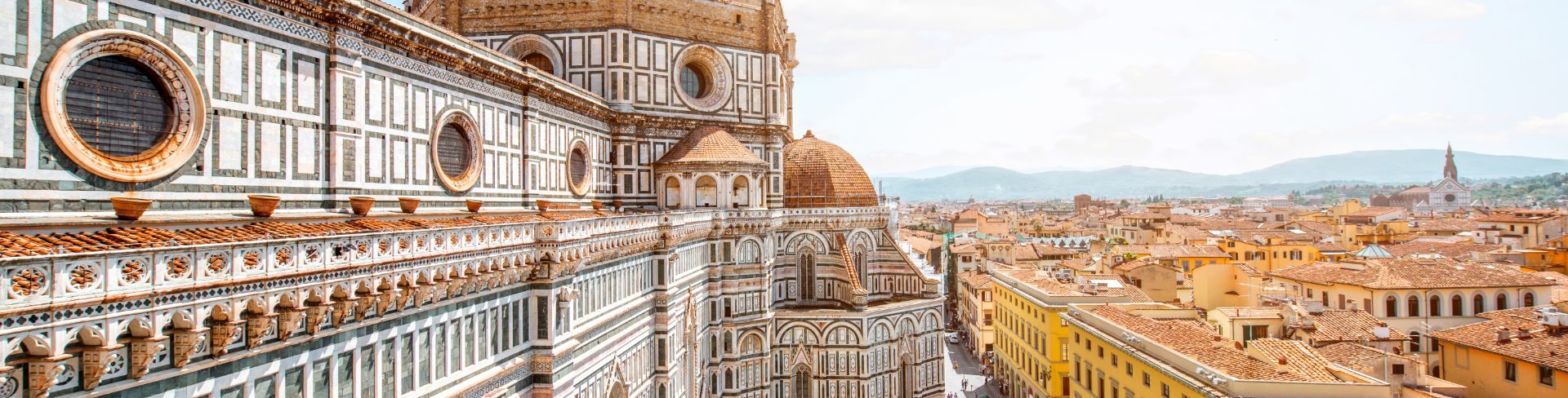 A view of a large dome of a Renaissance period cathedral with the cityscape of Florence in the background.