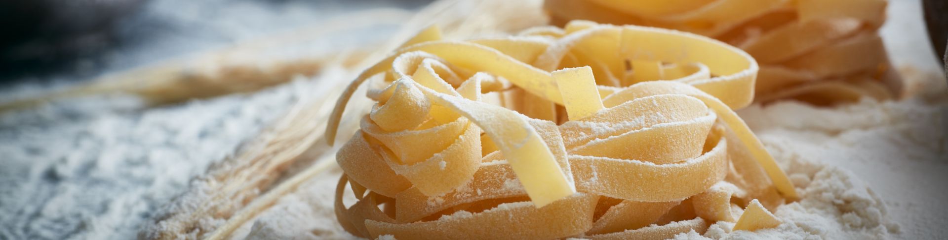 Piles of fresh homemade pasta resting in flour on a table.