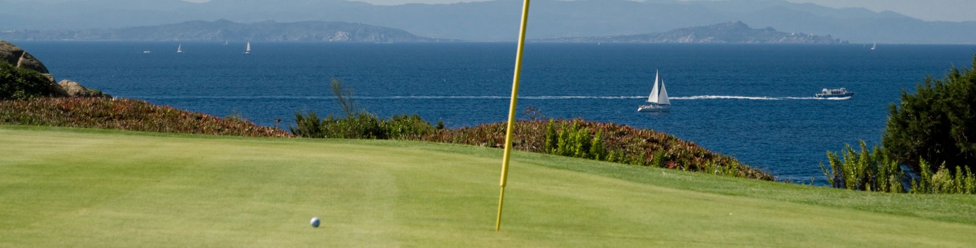The flag for hole 11 at a golf course on the coast overlooking the ocean.
