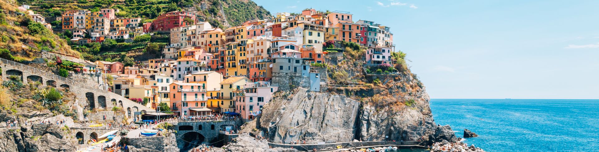 Pastel colored buildings on a hillside overlooking bright blue waters. 