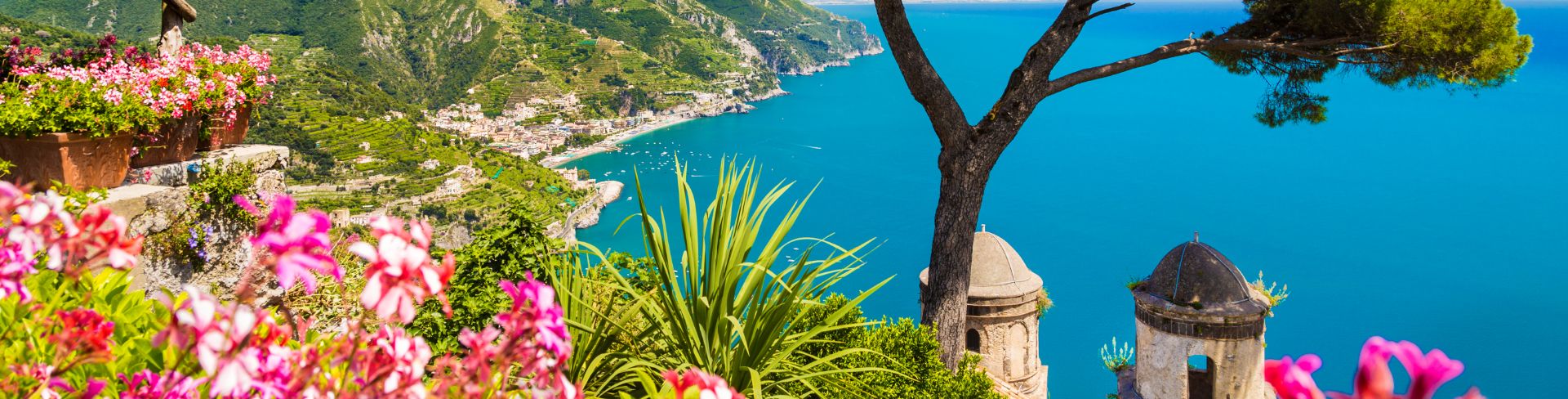 The view of the Amalfi Coast from a mountain-top garden of pink flowers and trees.