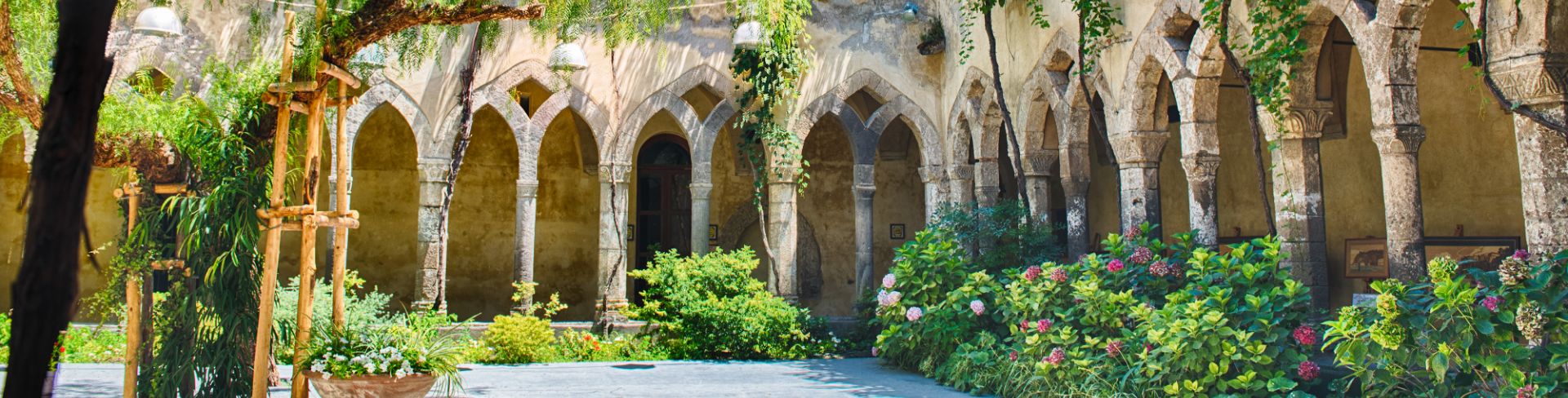 The courtyard inside a cloister, covered in vines and other beautiful greenery.