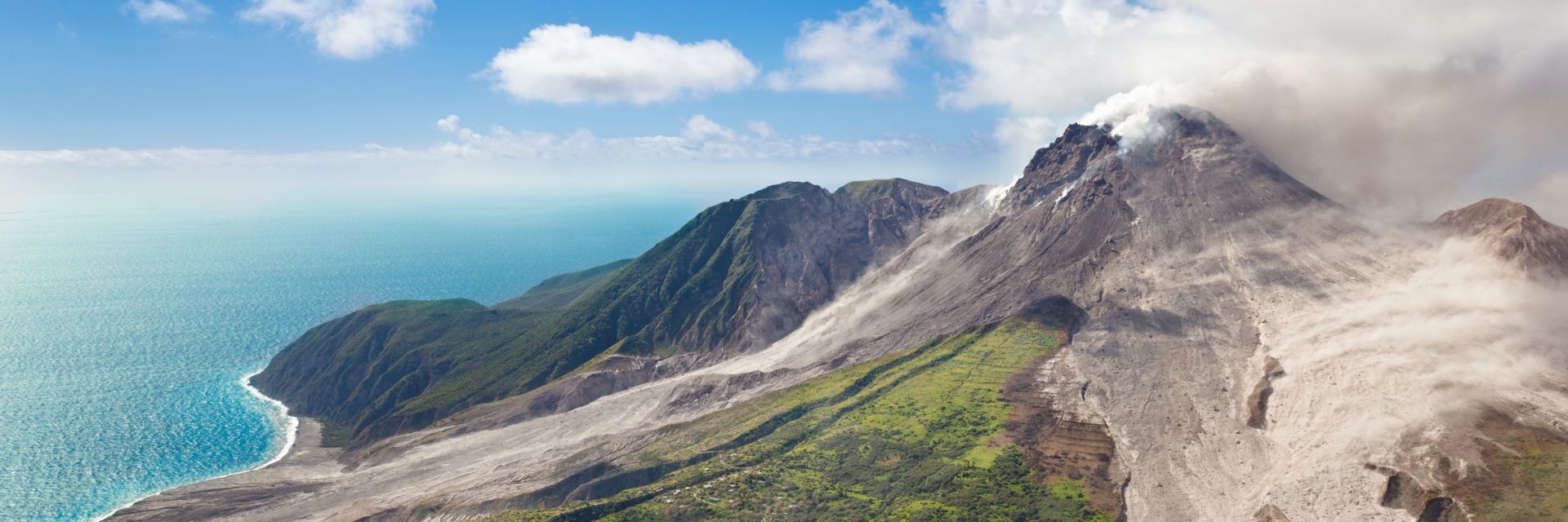 A view from the clouds atop a mountain overlooking bright blue sea.