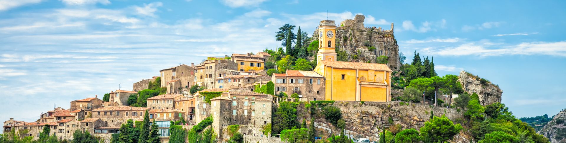 A small old French village sitting atop a lush green hill.