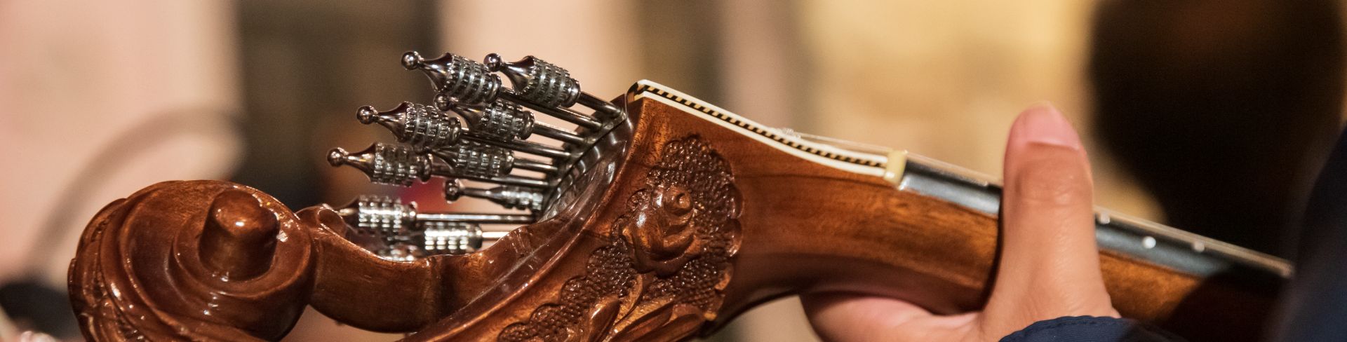 A close-up look at the intricate carved wood head of a Portuguese fado guitar.