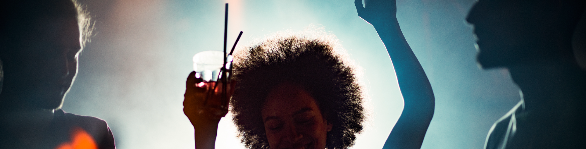 A woman is celebrating and dancing with a cocktail.