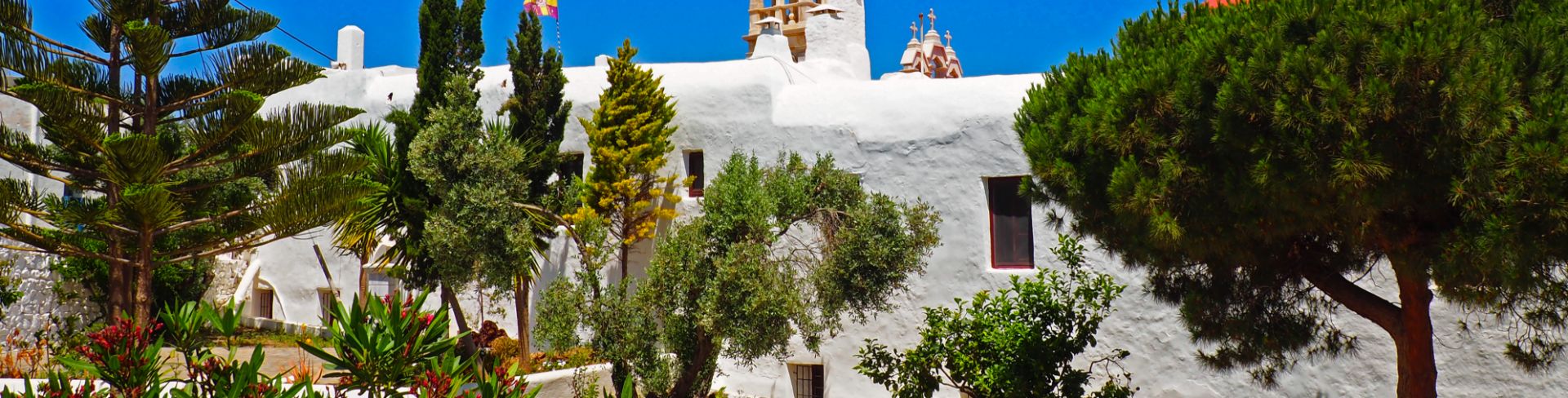 A whitewashed monastery under blue skies on the island of Mykonos.