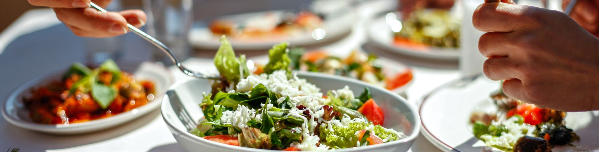 A couple eating lunch at a table full of fresh salads and appetizers.