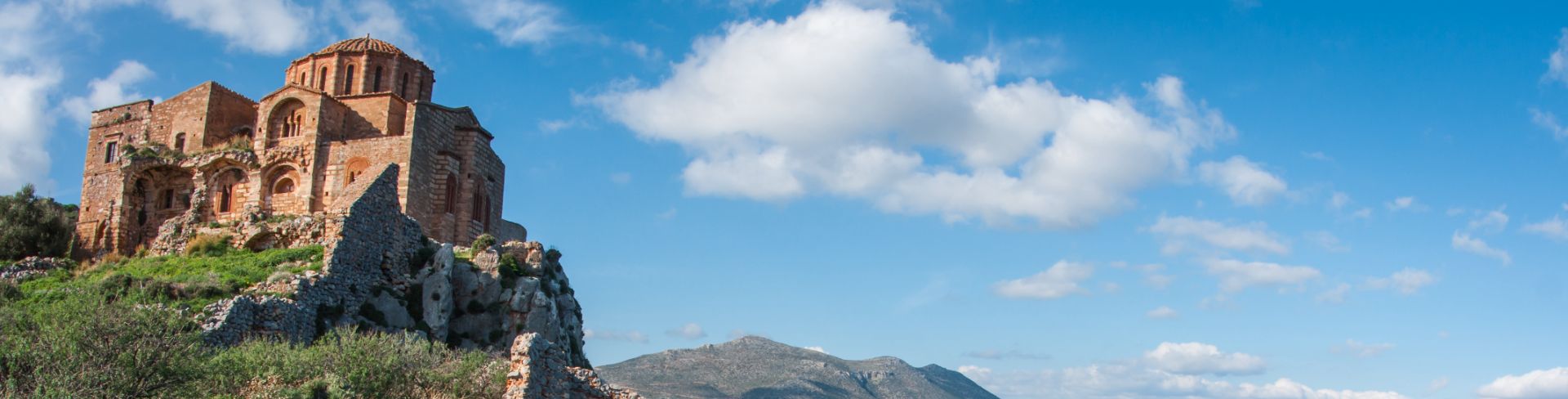 A medieval church on top of a cliff overlooking the sea and Peloponnese, Greece, in the distance.