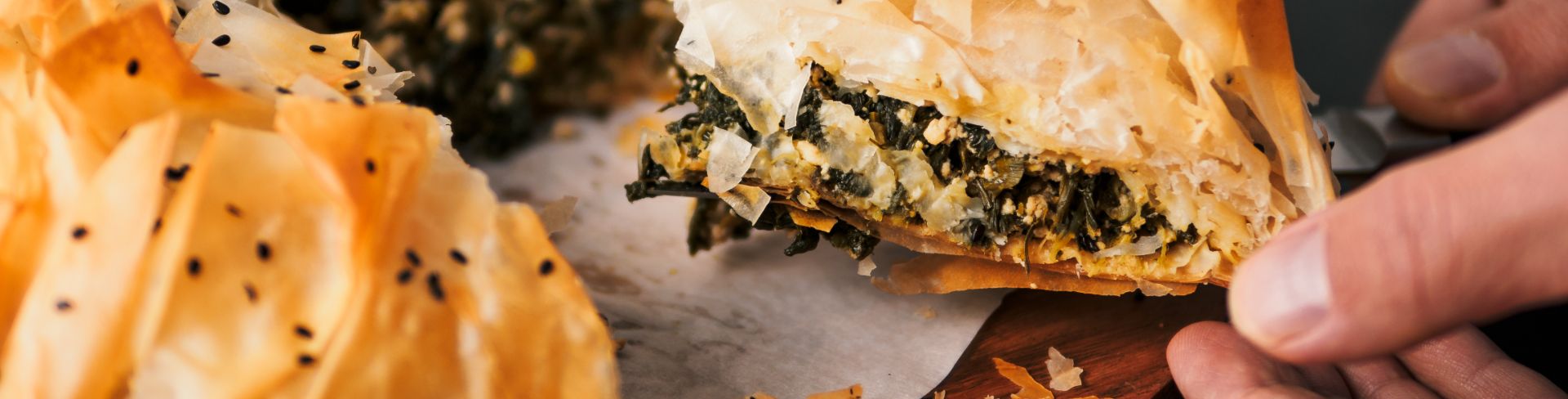 A close-up look of someone taking a slice of spanakopita. 