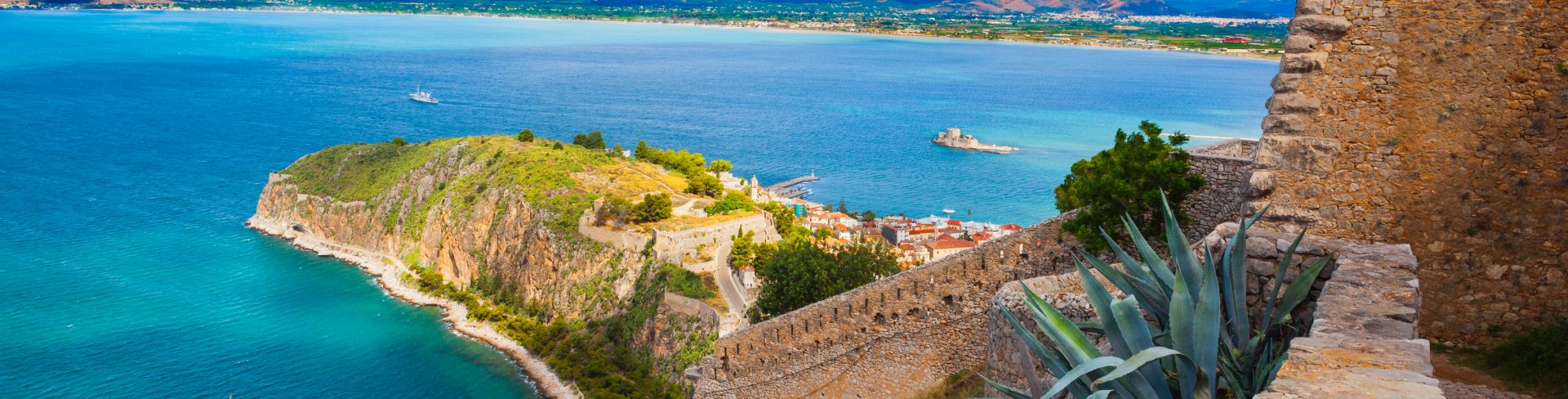 The ruins of a fortress on a hilltop overlooking the sea and Greek isles.