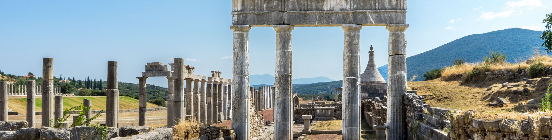 The ruins of the ancient city of Messini, featuring stone walls and columns.