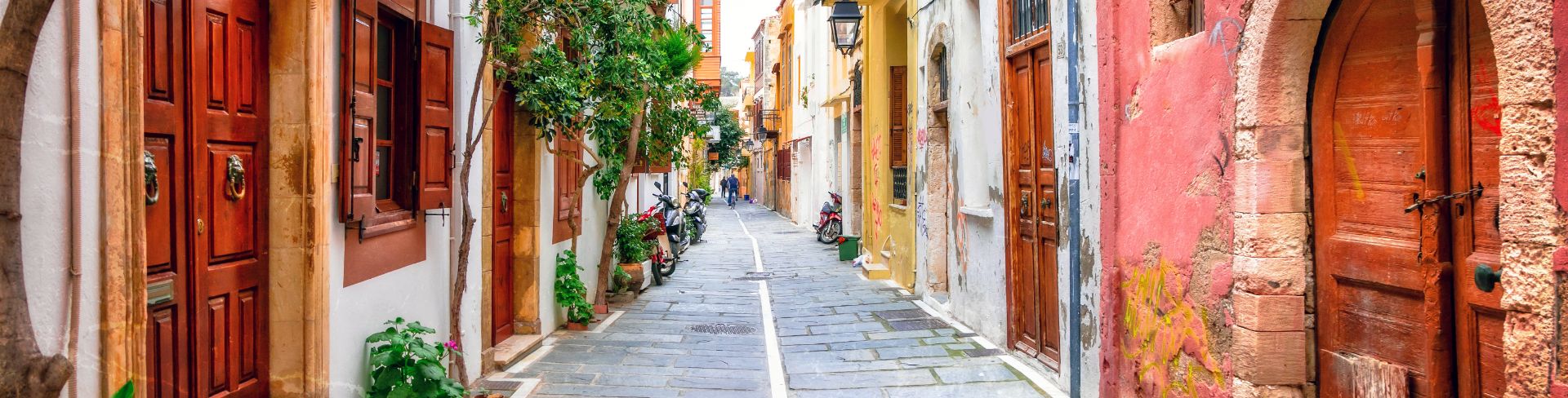 A traditional street in an old Greek town, lined with old colorful buildings.