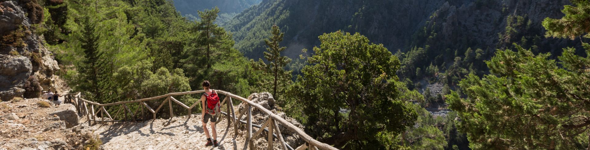 A woman hikes down stone stairway overlooking a beautiful, lush gorge.