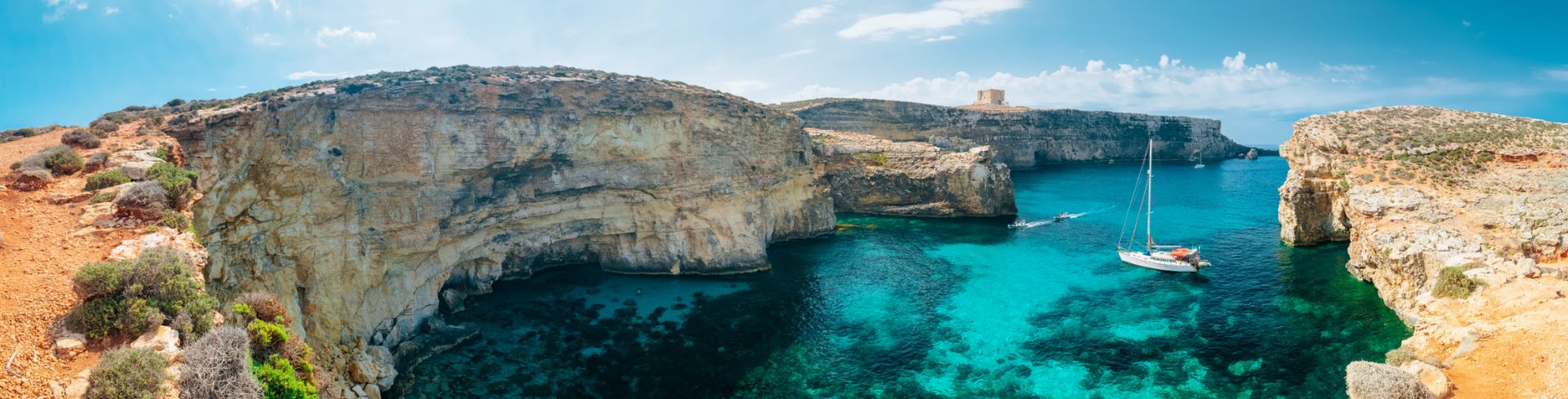 The view from a cliff looking down into a crystal clear blue-green lagoon.