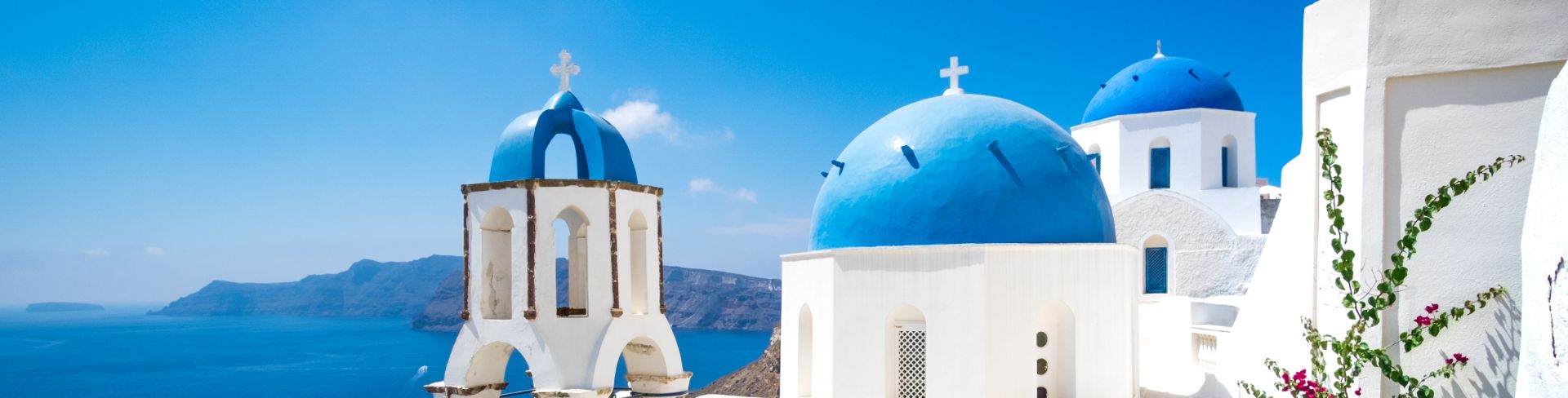 White washed buildings soak up the sun under the bright blue sky. 