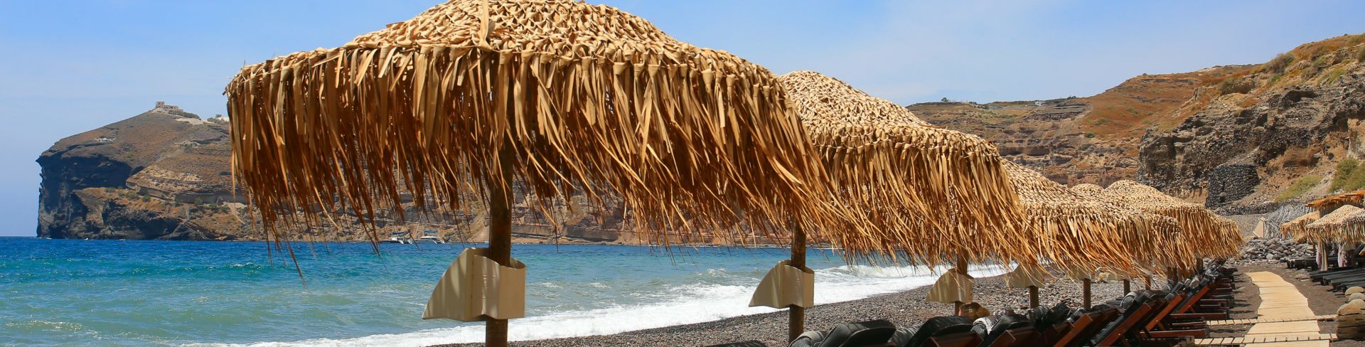 Relaxing beach chairs and umbrellas face the waters edge.