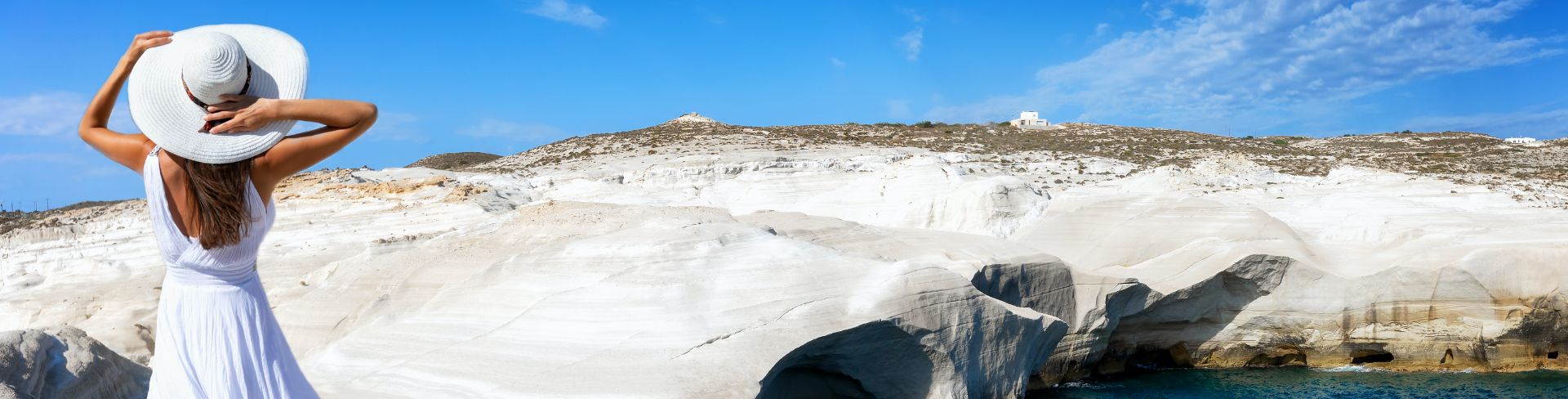 A woman stands on the rocky beaches of Milos.