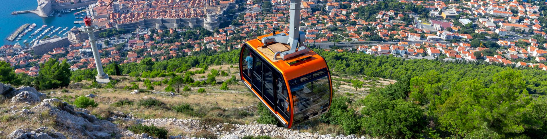 A colorful cable car rides past with stunning aerial views of the city and water.