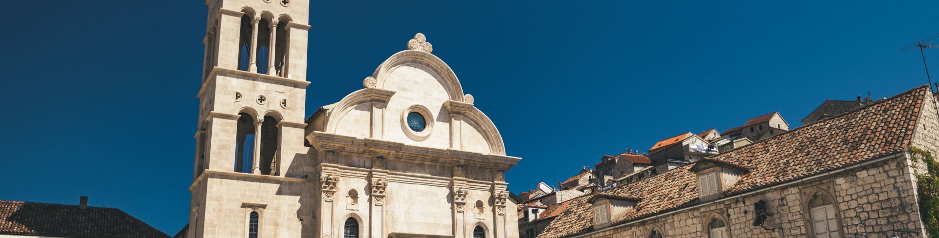 The Franciscan Monastery and bell tower stand against the dark blue sky.