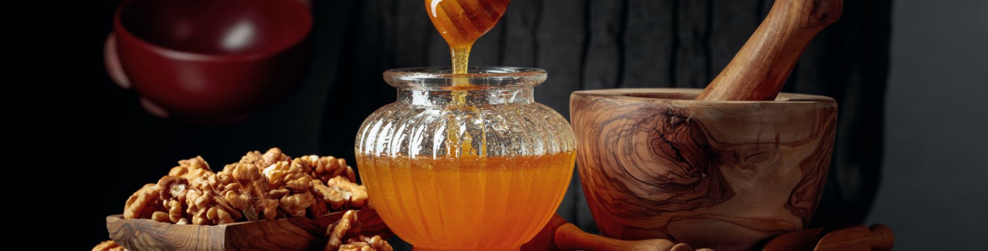 A man in a dark sweater serves honey and nuts.