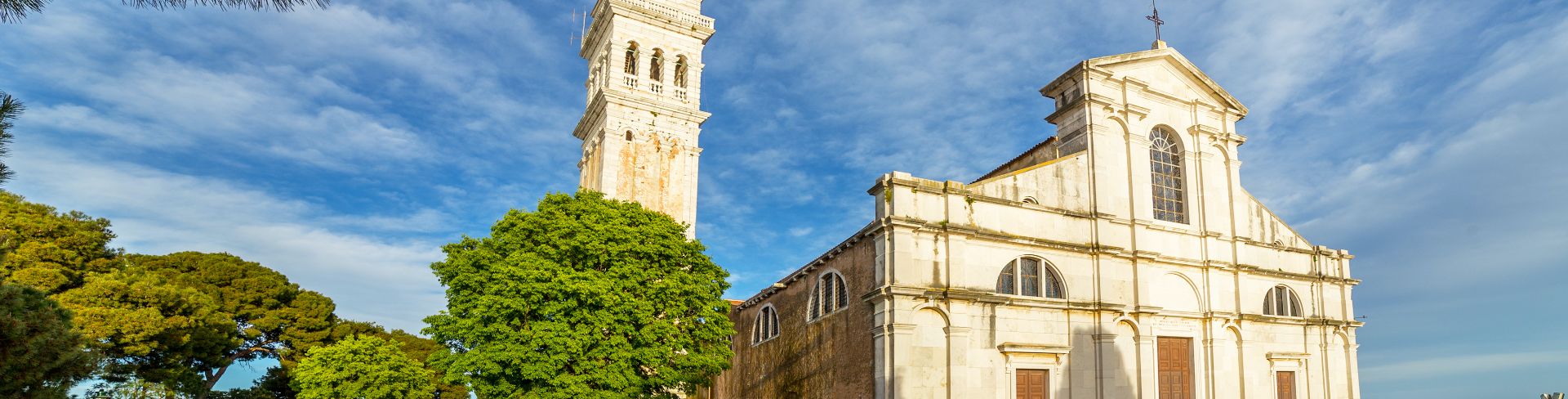 A white church sits next to a bell tower under the blue sky.