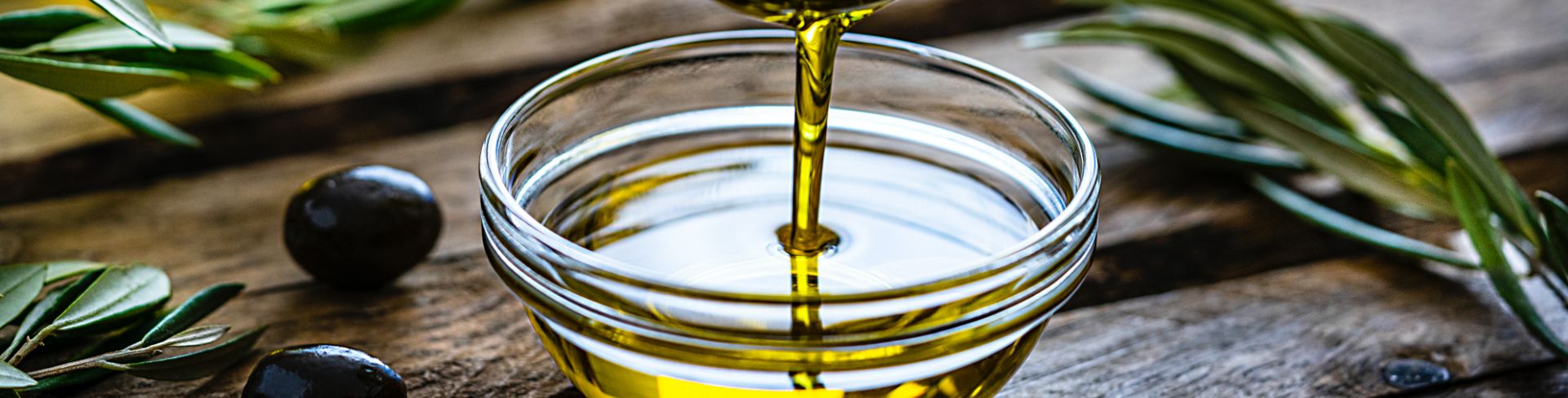 Golden olive oil pours into a small serving bowl.