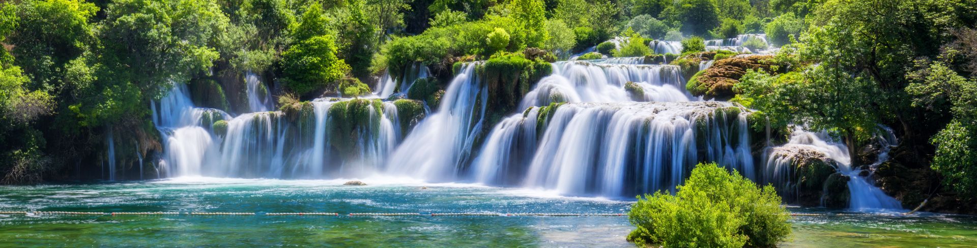 Amid the lush green forest is a series of roaring waterfalls.