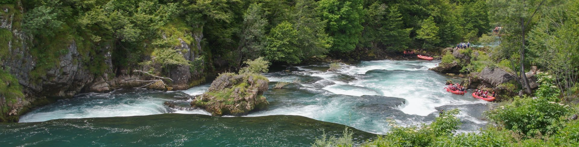 The white-capped rapids of the Cetina river sit between green forests.