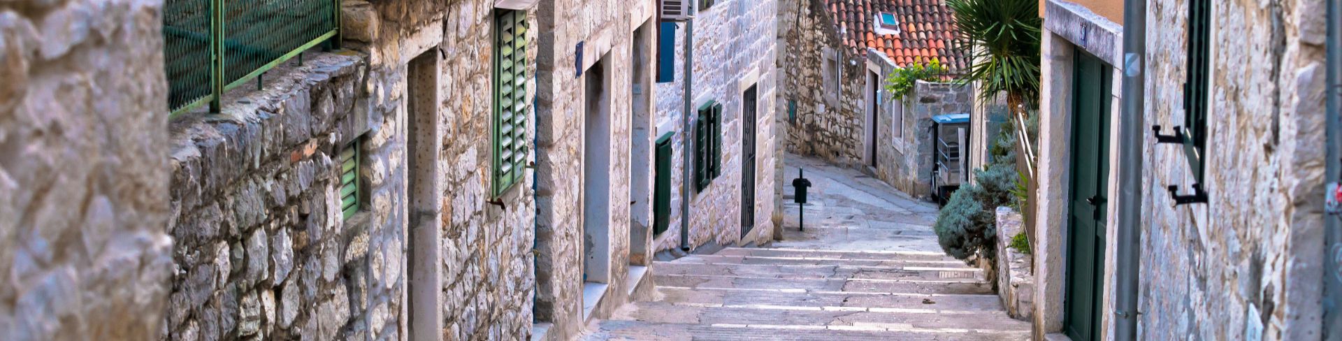 City steps weave between stone buildings with orange roofs.