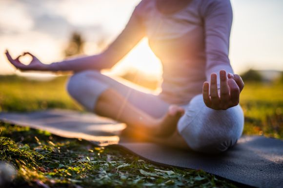 The sun's rays light a woman doing yoga outside