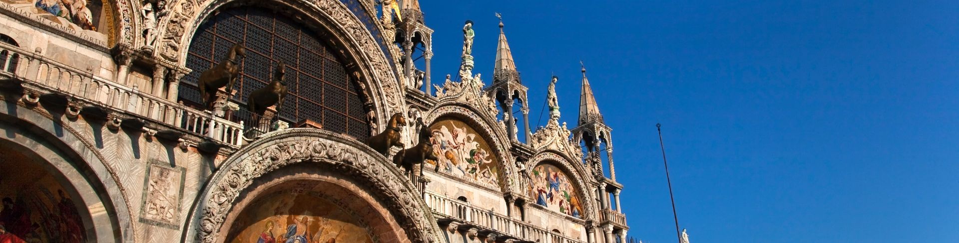 Basilica di San Marco sits under a bright blue sky.