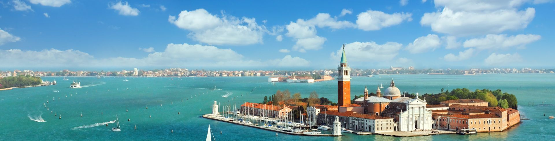The Venice lagoon sits in blue-green waters and under bright blue skies.