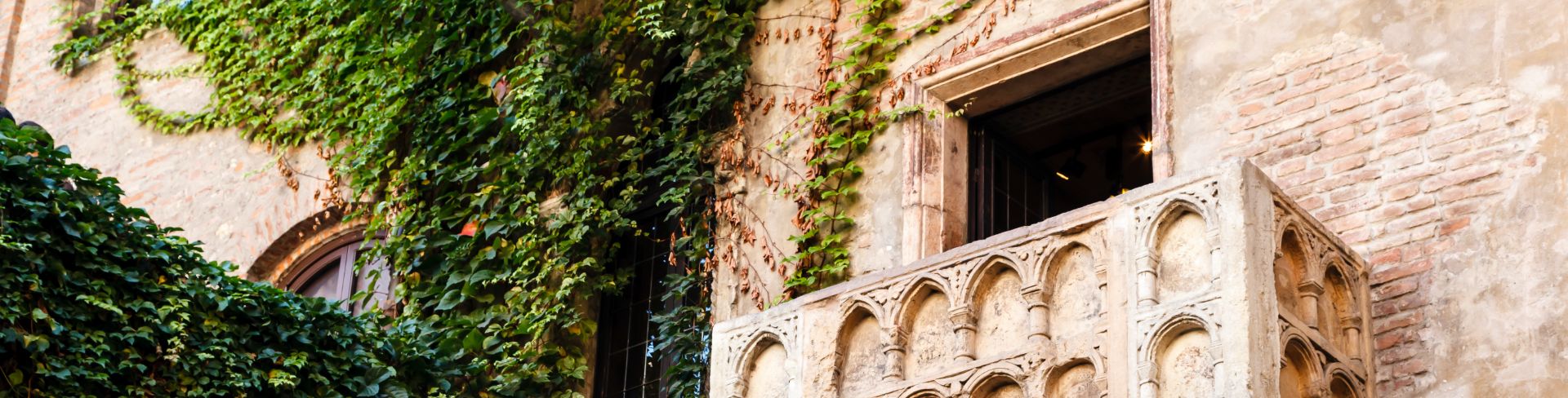 The balcony that inspired Romeo and Juliet sits next to green vines.