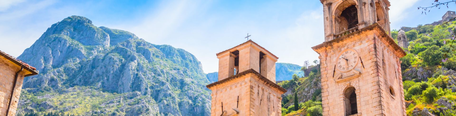 A building sits under the bright blue sky with mountains in the background. 
