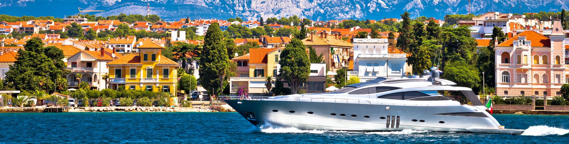 A yacht speeds by the city shore line.
