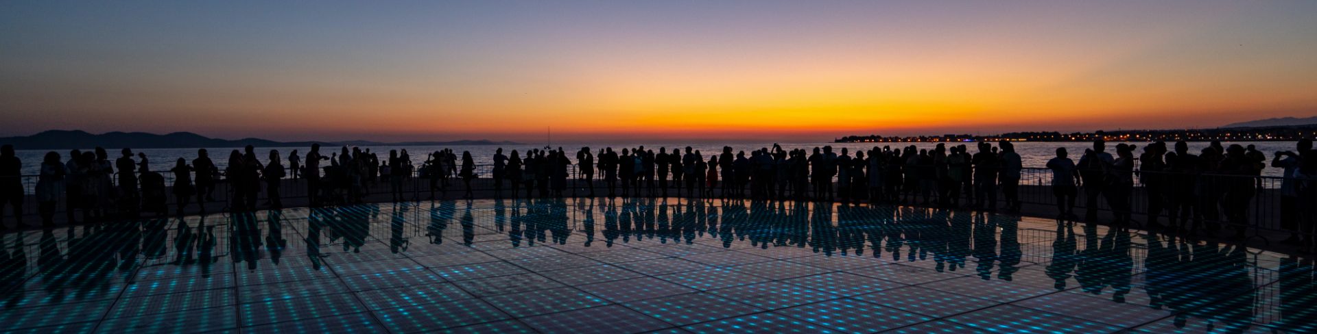 A large group of people enjoy the sunset in Zadar.