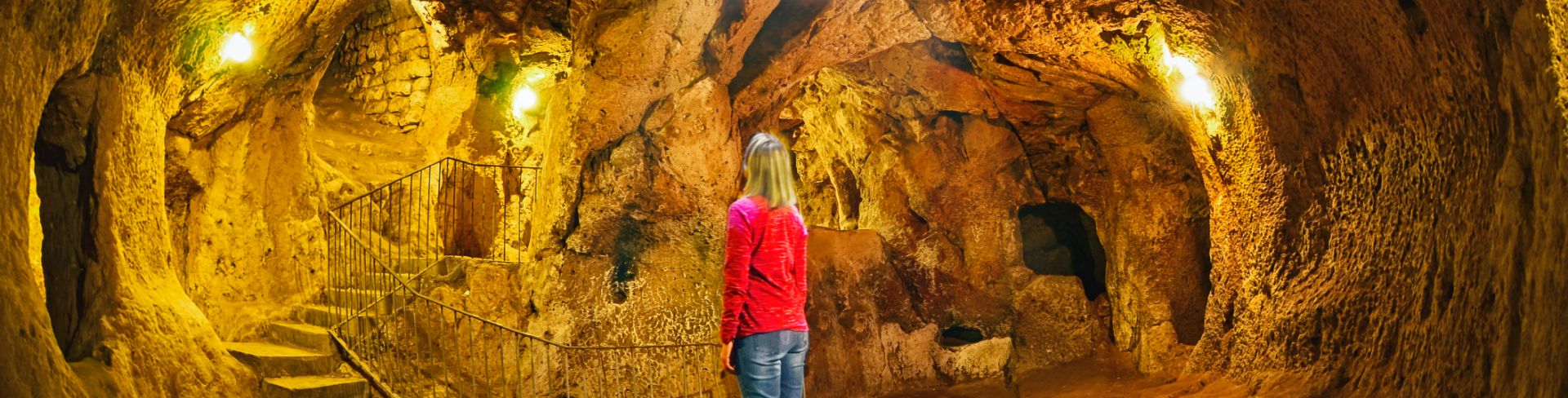 A woman stands inside a cave.