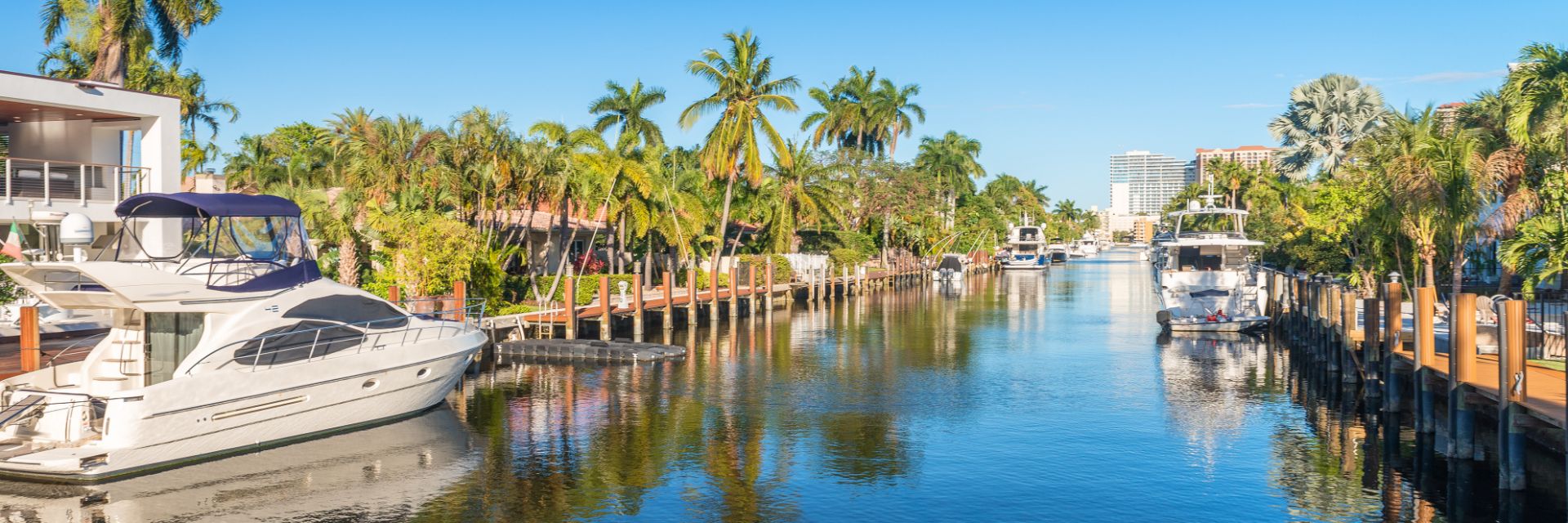 A canal in Fort Lauderdale, Florida, lined with docks, yachts and palm trees on either side.