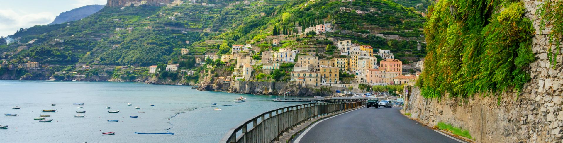 The view of an Italian village of pastel-hued buildings on a cliffside.
