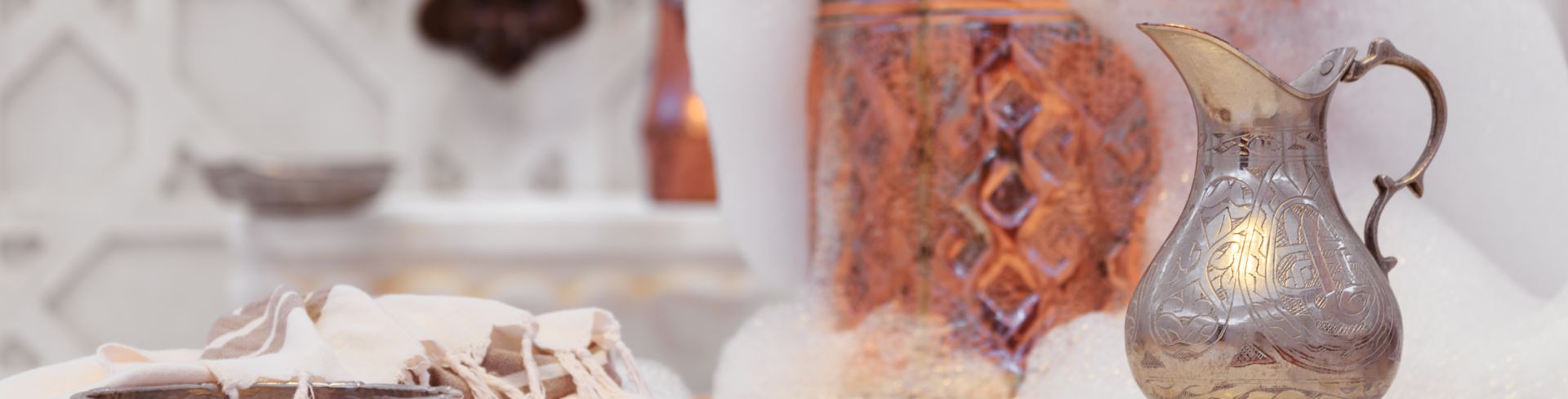 A water jar, towel and copper bowl with soap foam in a Turkish hammam.