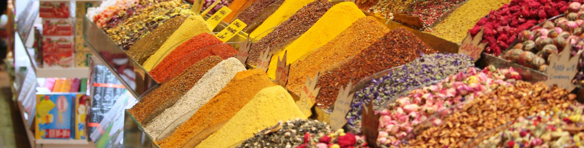 Multiple rows of colorful spices and teas at a bazaar.