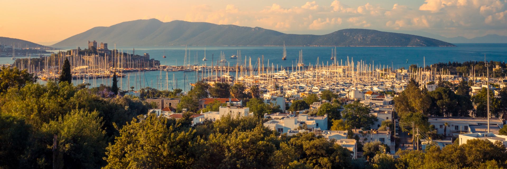 Looking out over a Bodrum harbor at sunrise with a medieval castle in the background.