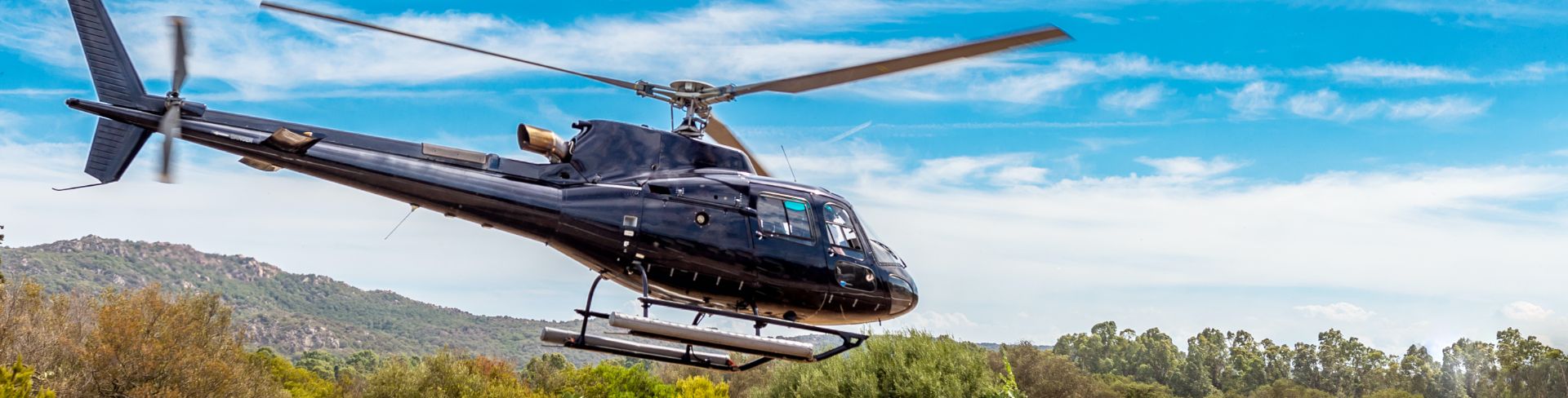 A black helicopter comes in for landing in an airfield on Corsica.