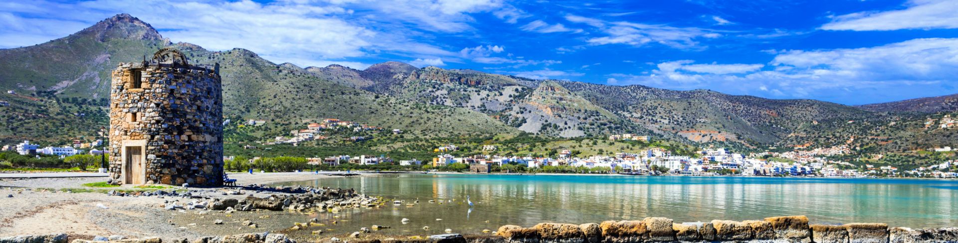 The ruins of an old windmill and crystal waters in Elounda.