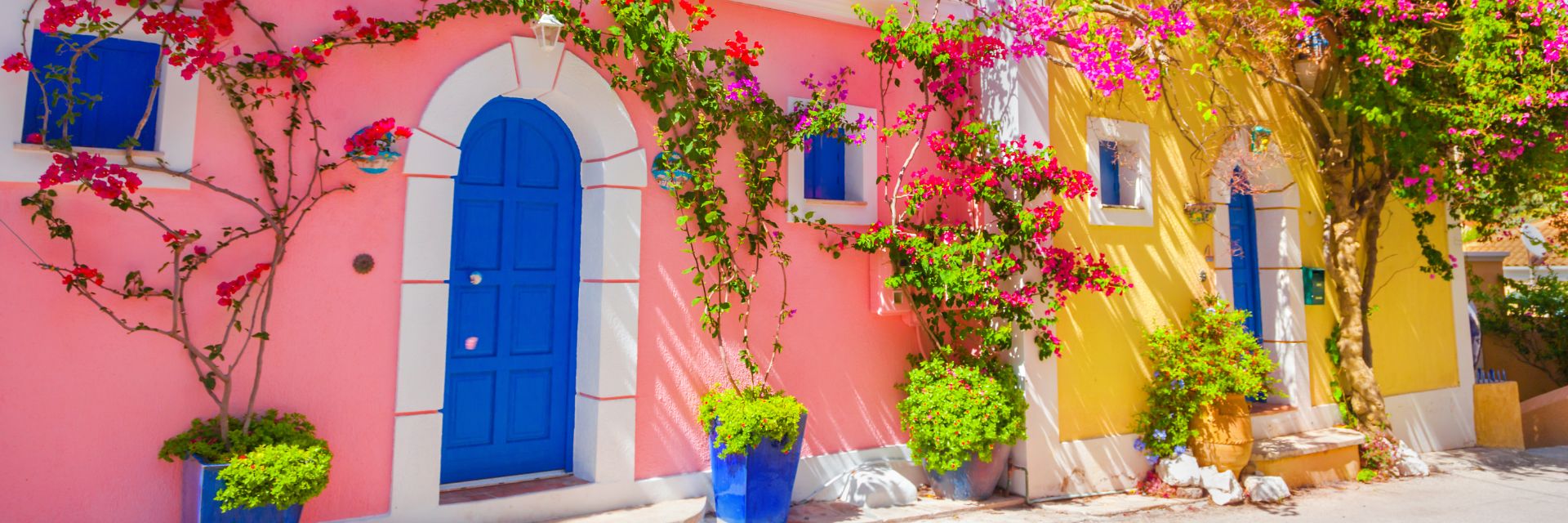 A pink house with a blue door on a street in Kefalonia, Greece.