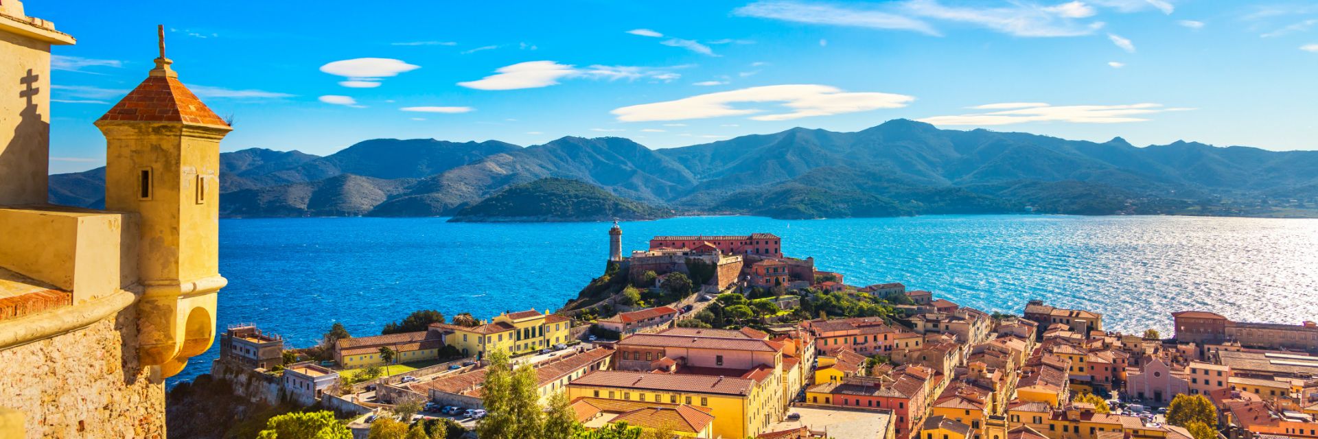 An aerial view of Portoferraio, Elba, looking towards the water and rolling mountains beyond.