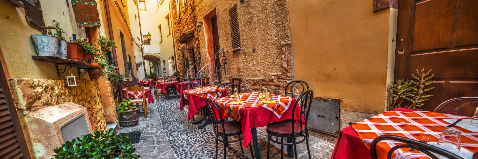 Rustic tables and chairs by a trattoria in Sardinia, Italy.